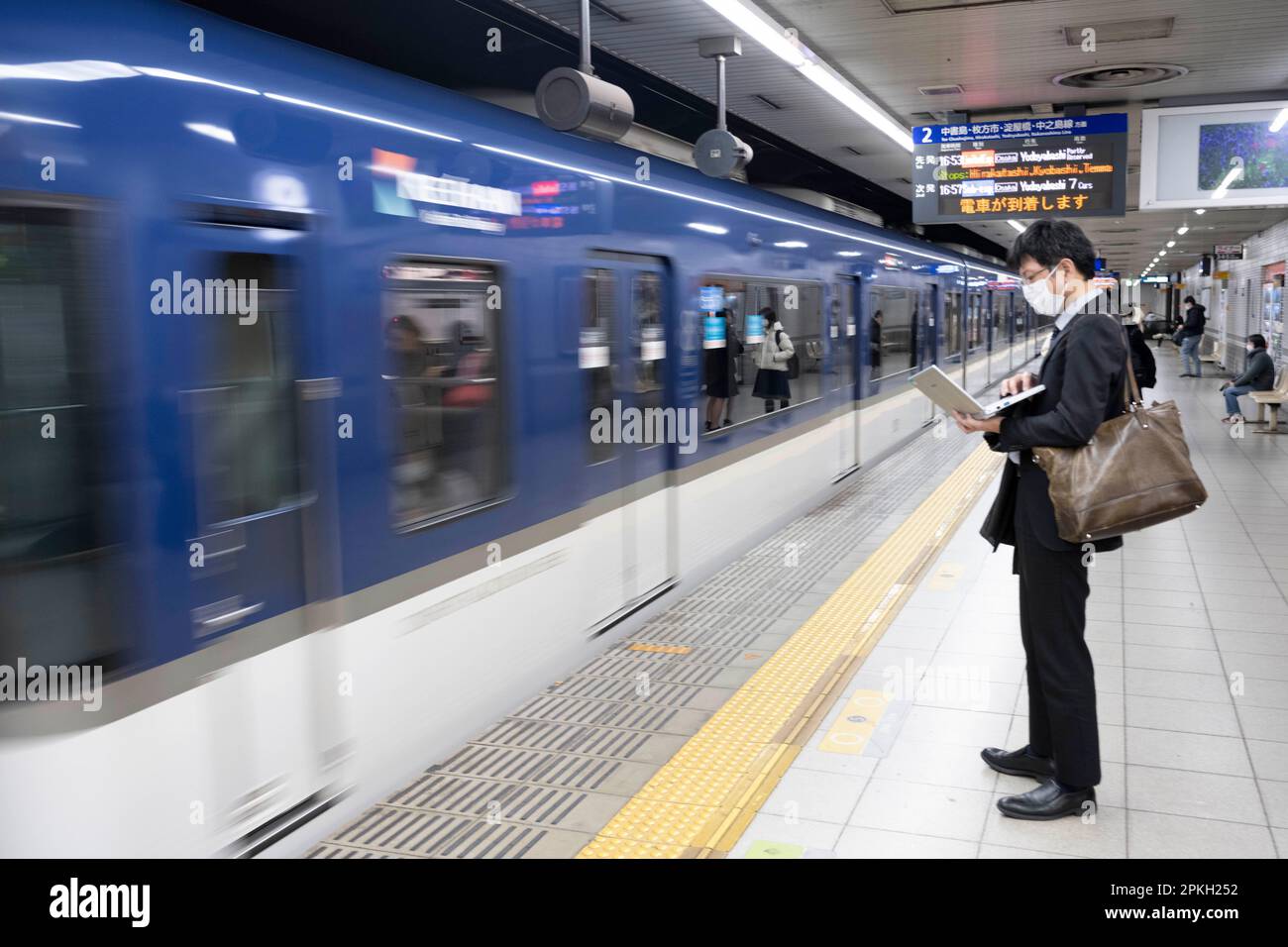 Kyoto, Japan. 6. März 2023. Ein Verkäufer arbeitet an seinem Laptop, wenn ein Zug der Keihan Main Line am Bahnhof ShichijÅ ankommt. Die Keihan Main Line (ä°¬é˜ªæœ¬c·š, Keihan-honsen) ist eine Eisenbahnstrecke in Japan, die von der Keihan Electric Railway betrieben wird. Es verkehrt zwischen dem Bahnhof SanjÅ in Kyoto und dem Bahnhof Yodoyabashi in Osaka. Kyoto ist die ehemalige Hauptstadt Japans und heute die Hauptstadt der Präfektur Kyoto. Es liegt in der Kansai-Region auf der Insel Honshu. Kyoto ist bekannt für seine vielen Tempel, Schreine und Gärten. Es ist auch die Heimat des Kaiserpalastes von Kyoto, der ehemaligen Residenz des Kaisers von Japan Stockfoto