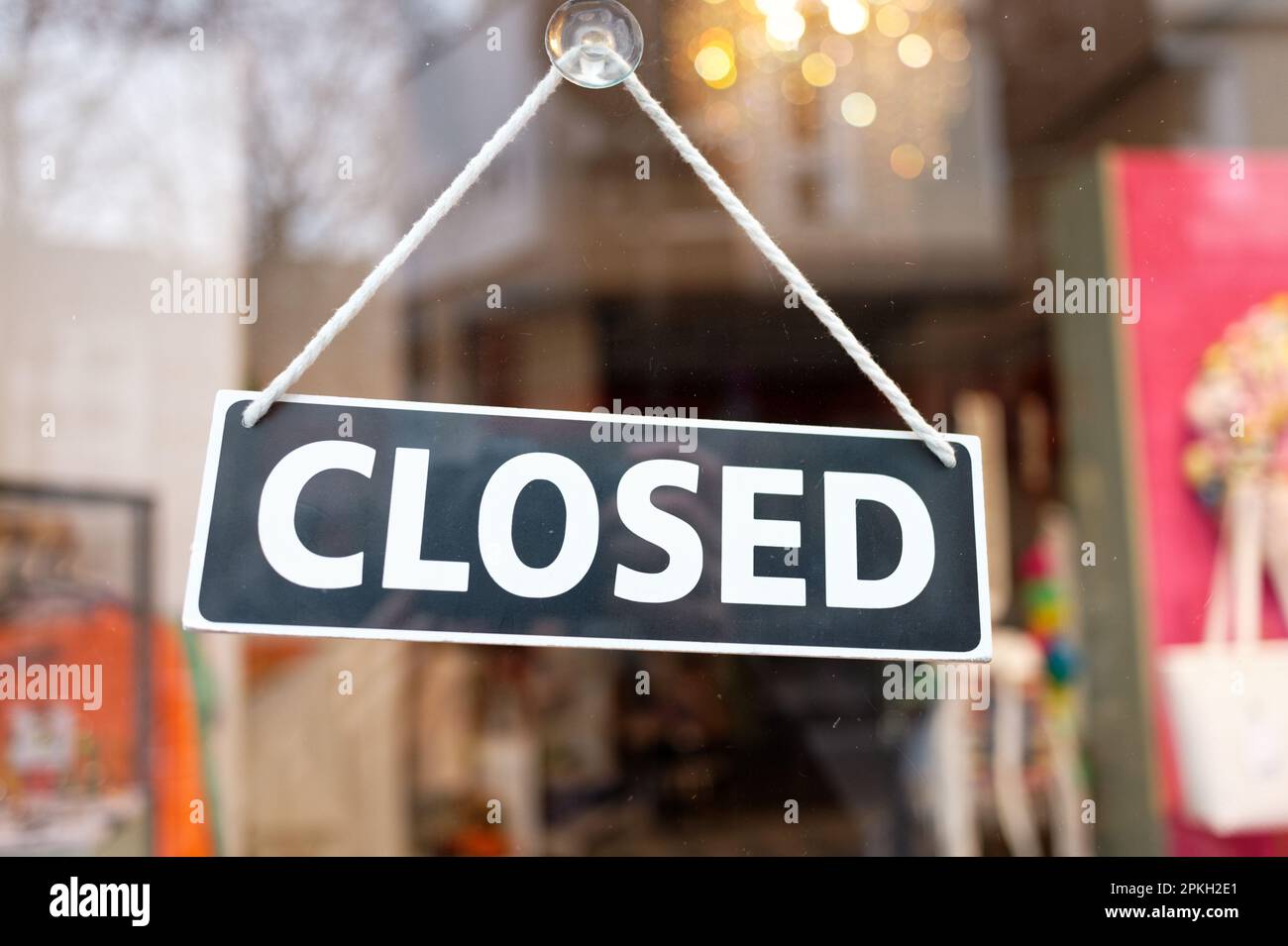 Ein „geschlossenes“ Schild ist mit einem Saugnapf am Glas der Eingangstür einer Modeboutique angebracht Stockfoto