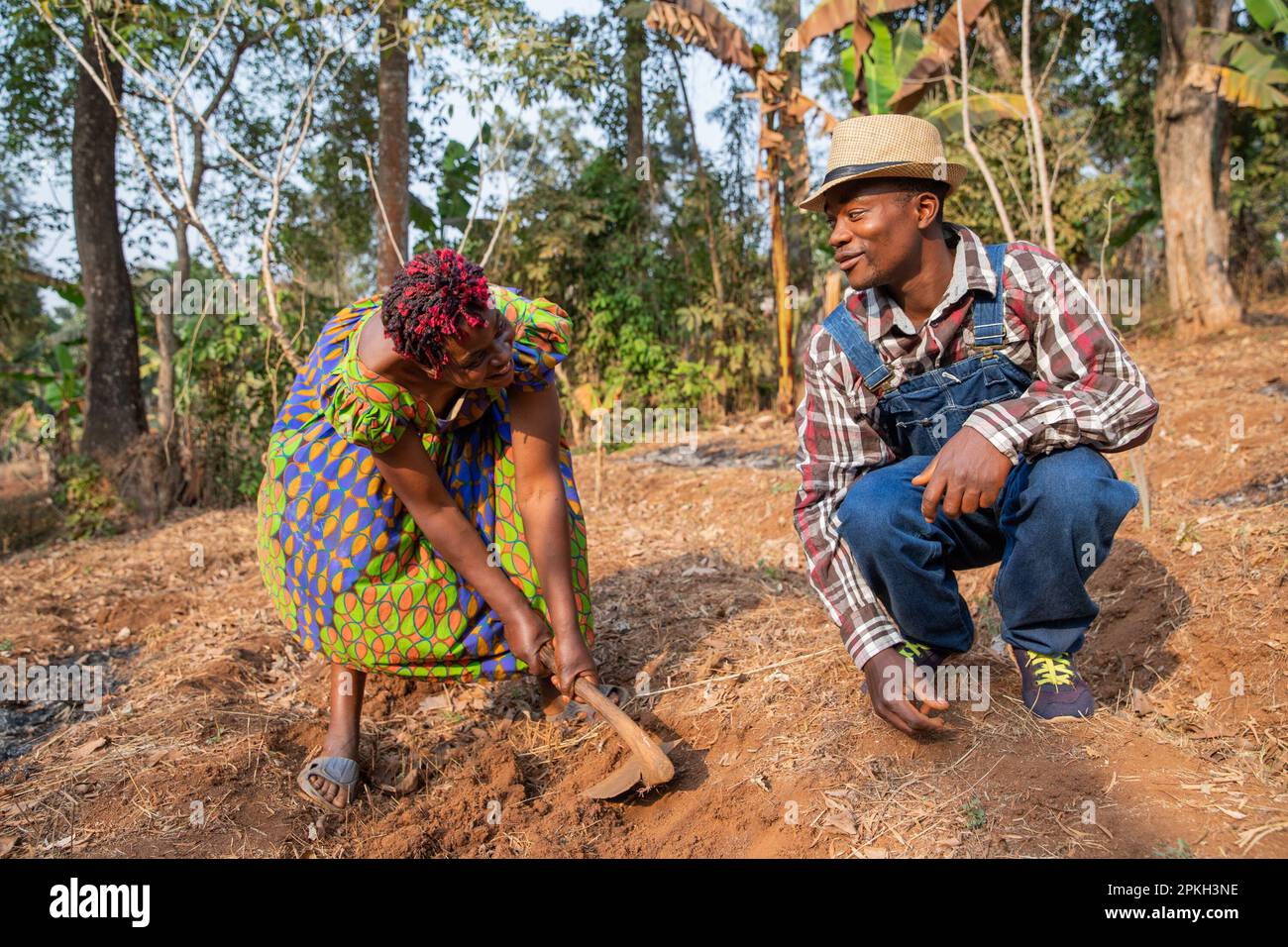 Zwei afrikanische Bauern hacken die Felder und unterhalten sich über die Landwirtschaft in Afrika. Stockfoto