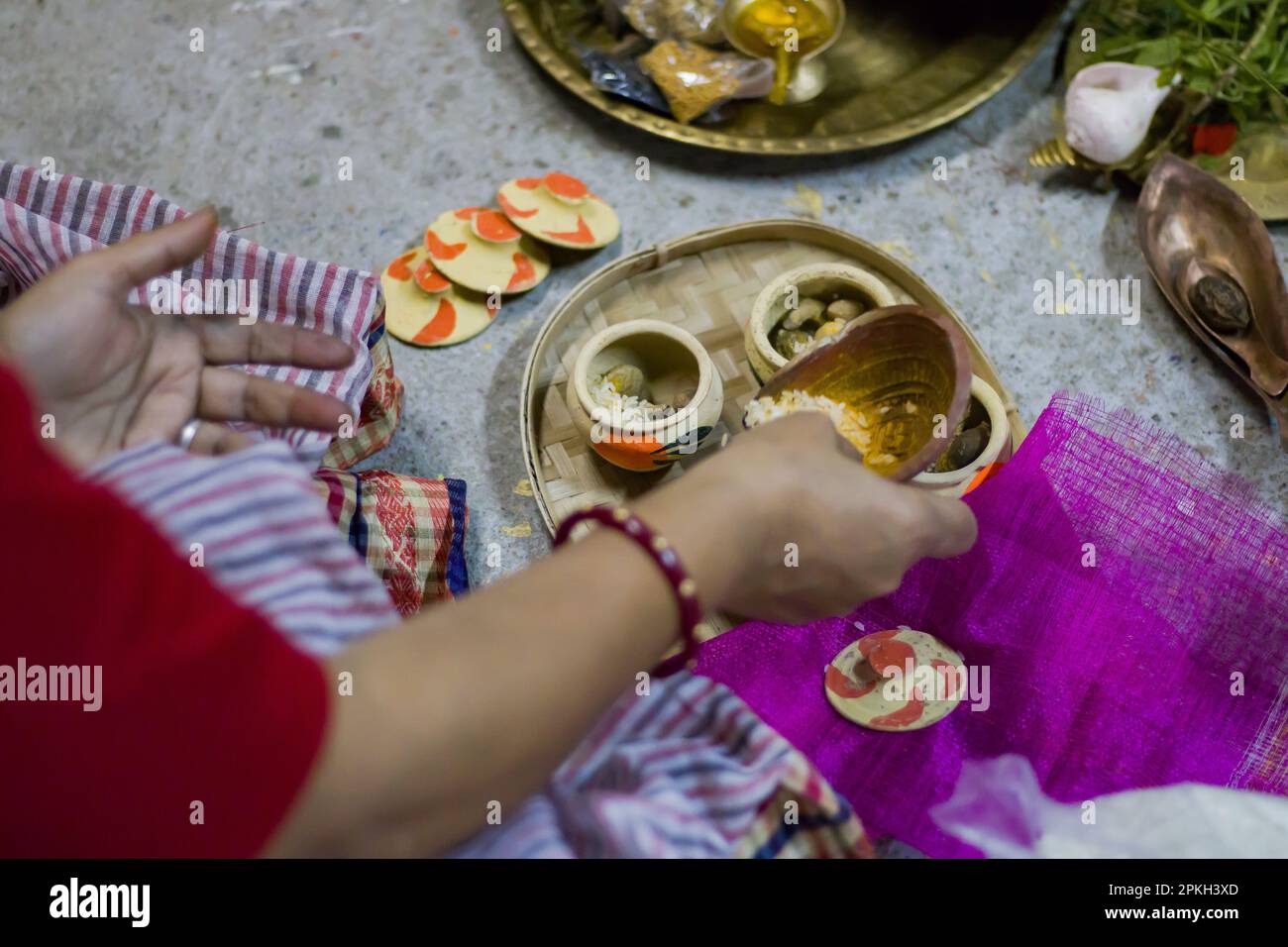 Bordala wird von einer hinduistischen Frau in traditioneller Kleidung während einer bengalischen Hochzeit oder Puja-Ritualen zubereitet. Bordala ist kulo oder ein Bambusbehälter gefüllt Stockfoto