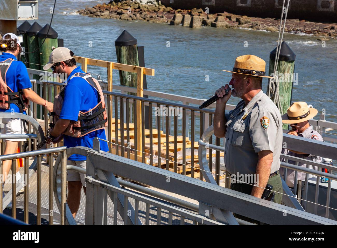 Die Besatzung der Fähre sichert das Boot, während ein Park Ranger Besucher des Fort Sumter National Monument in Charleston, South Carolina, USA, willkommen heißt Stockfoto