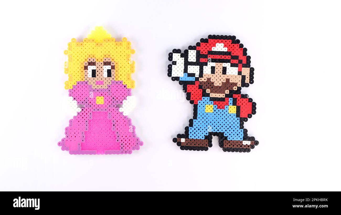 Beliebtes 8-Bit-Spielzeug aus Kunststoff Super Mario und Prinzessin Peach auf weißem Hintergrund. Super Mario Handgemachtes Spielzeug von Perler Perlen auf Weiß. Gatineau, QC Kanada Stockfoto