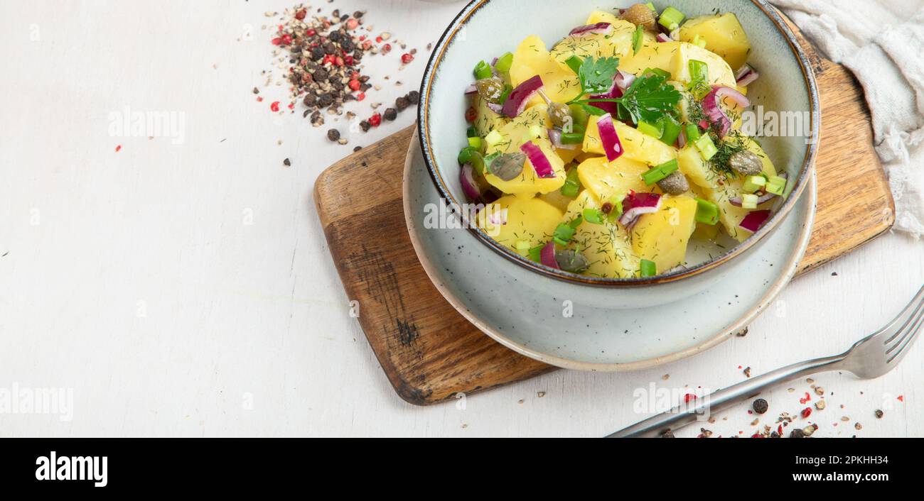 Deutsche Küche. Kartoffelsalat mit roten Zwiebeln und Olivenöl in einer Schüssel auf weißem Hintergrund. Draufsicht. Stockfoto