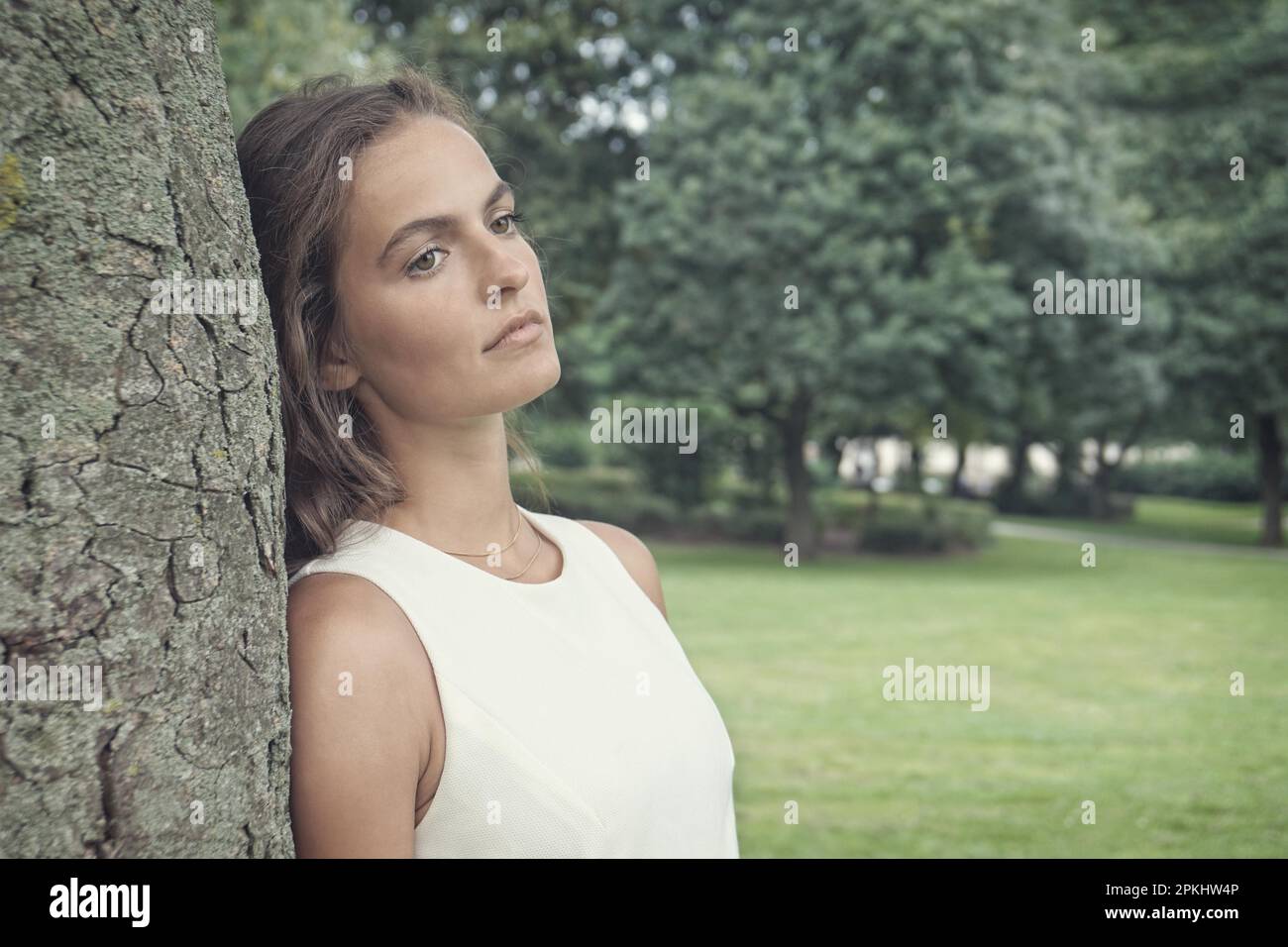Traurige junge Frau lehnte sich gegen Baum mit Vintage verblasst Filterwirkung Stockfoto