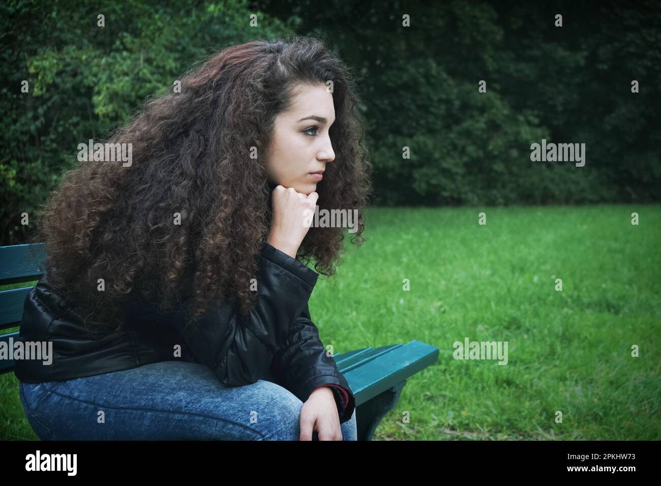 Traurige Frau, die auf der Parkbank sitzt Stockfoto