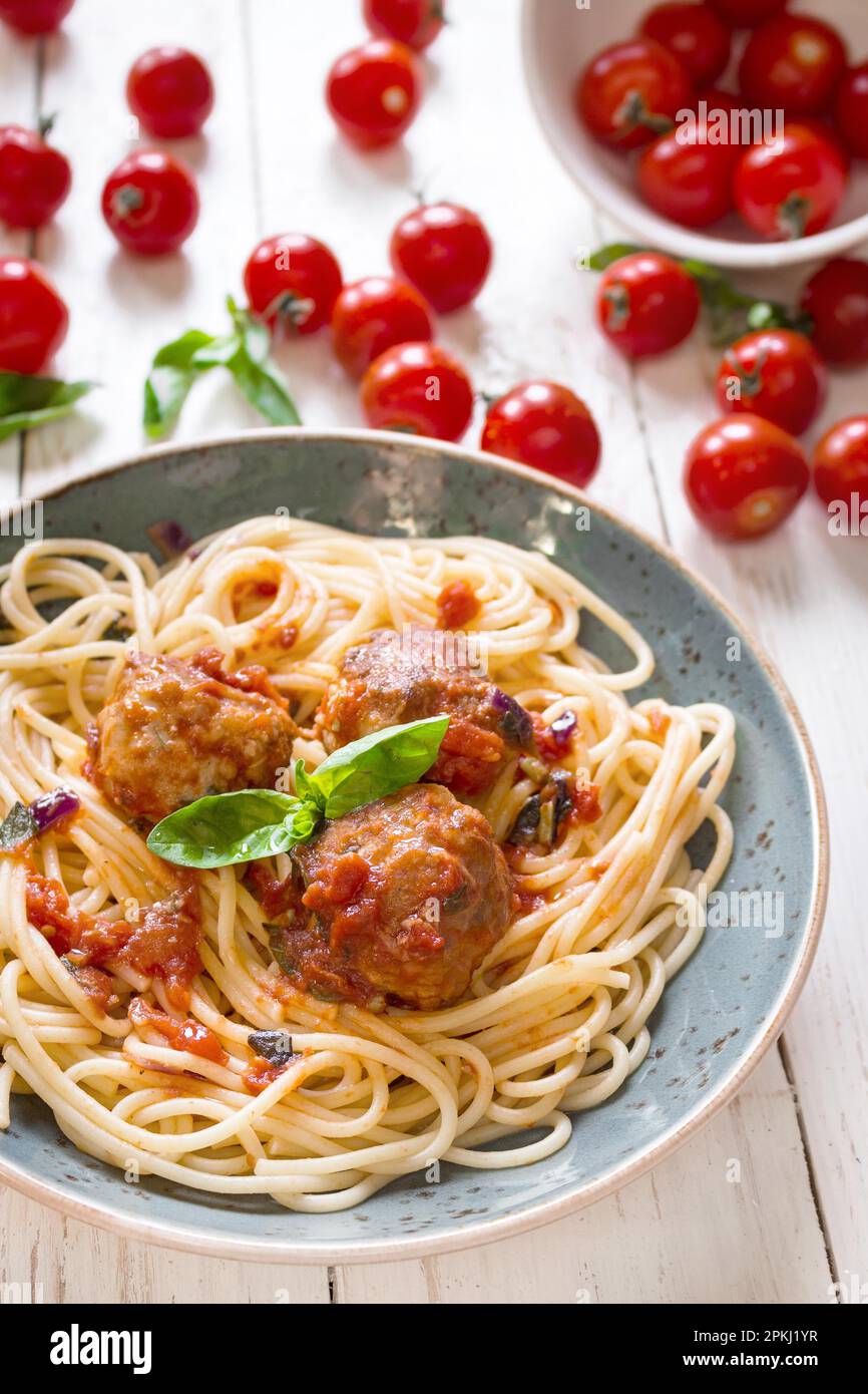 Nahaufnahme köstlicher Spaghetti mit Fleischbällchen und Tomatensoße auf einem Teller. Serviert auf einem weißen rustikalen Holztisch. Ein italienisch-amerikanisches Gericht. Stockfoto