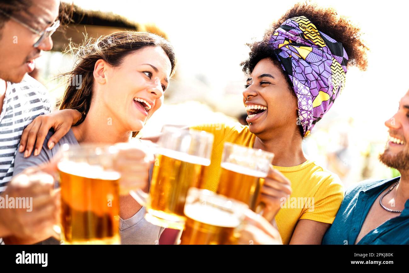 Trendige Multi-Rassenfreunde, die auf der Sommerparty am Strand einen Bären toasten - das Lebensstilkonzept für Speisen und Getränke mit verschiedenen jungen Leuten bei der Einstellung Stockfoto