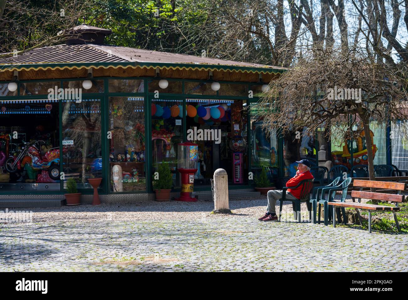 Rom, Italien, April 2023 ein Kiosk auf der Piazza Garibaldi, ein Alter Mann auf einem Stuhl in der Sonne Stockfoto