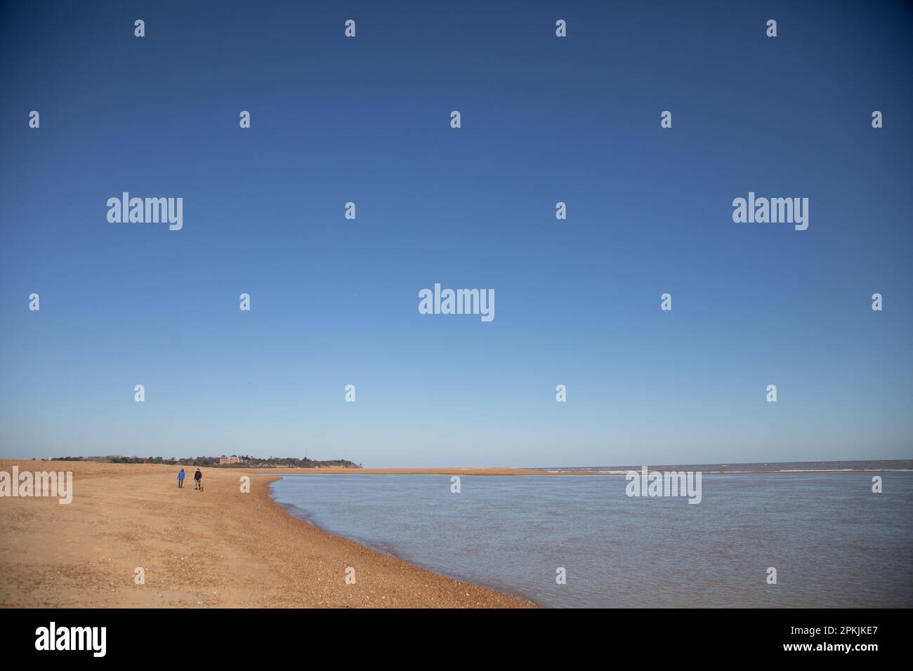 Zwei entfernte Spaziergänger an einem großen, leeren Strand in Felixstowe, Suffolk Stockfoto