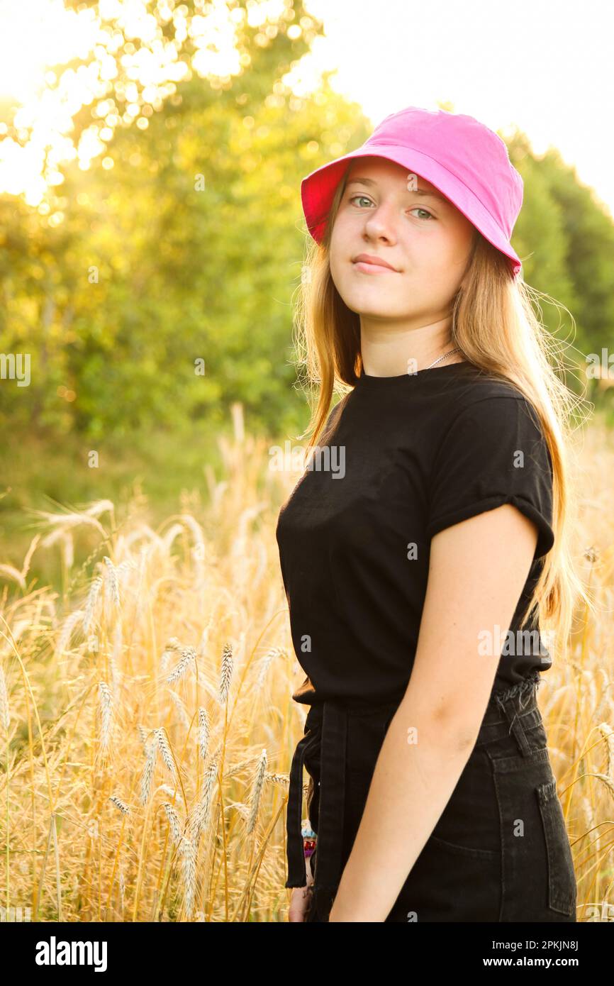 Sommermädchen. Ein hübsches lächelndes Teenager-Mädchen in einem Kleid, das vor einem gelben Sommerhintergrund steht. High Girl 12 oder 13 Jahre alt auf Sommerrasen. Vert Stockfoto
