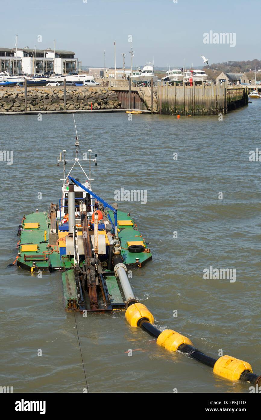 Ein Baggerboot im Hafen von West Bay, das Sand und Sedimente entfernt, die sich im Winter angesammelt haben. West Bay Dorset England GB Stockfoto