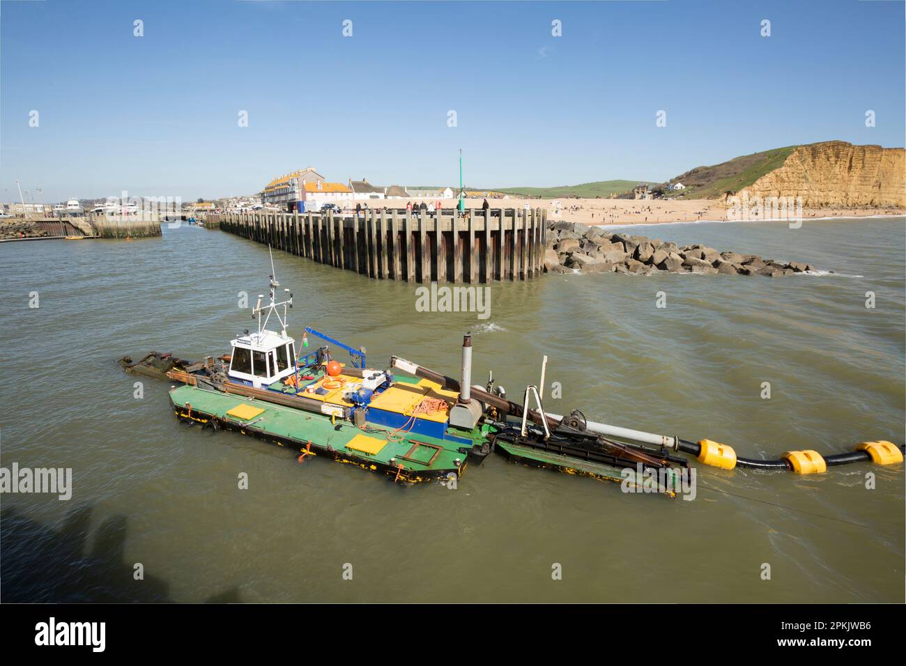 Ein Baggerboot im Hafen von West Bay, das Sand und Sedimente entfernt, die sich im Winter angesammelt haben. West Bay Dorset England GB Stockfoto