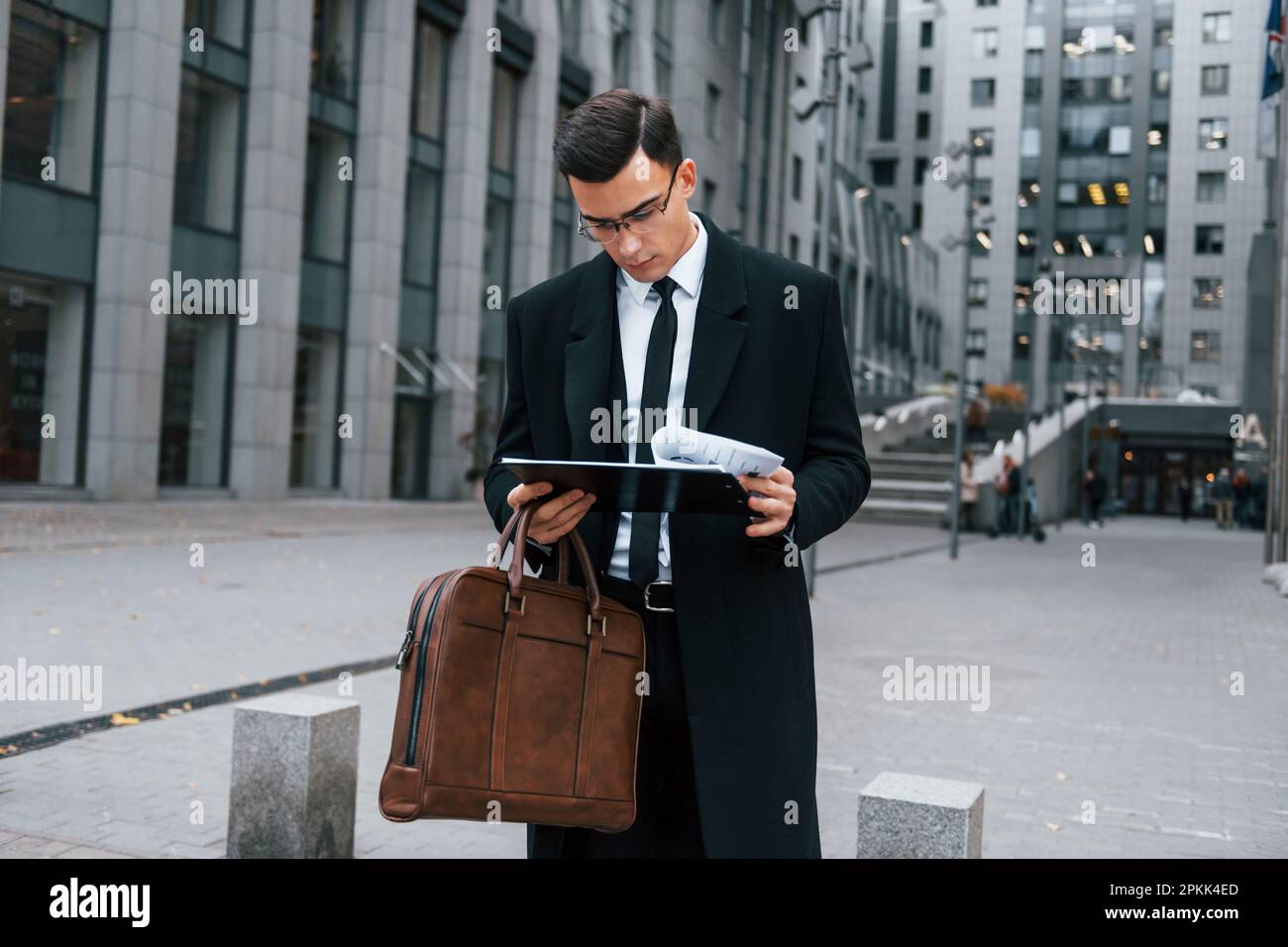 Dokumente aufbewahren. Ein Geschäftsmann in schwarzem Anzug und Krawatte  ist draußen in der Stadt Stockfotografie - Alamy