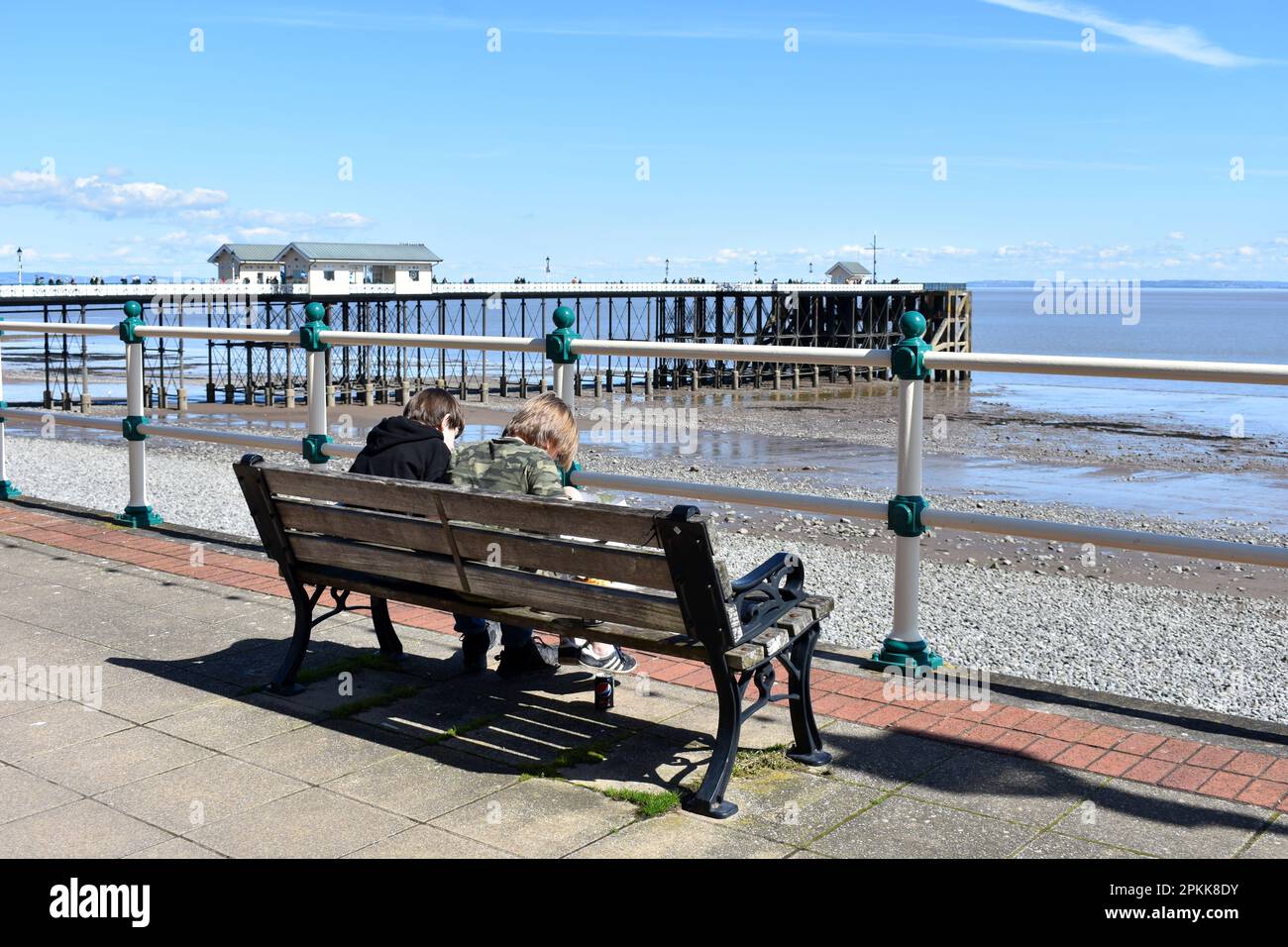 Zwei Jungs sitzen auf einer Bank in der Nähe von Penarth Pier, Penarth, Wales Stockfoto