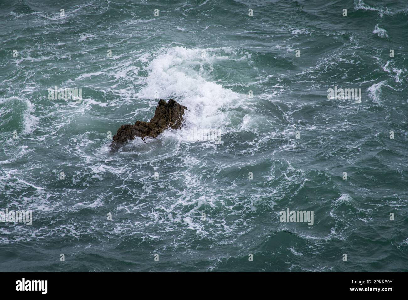 Großer dunkler Stein im Atlantischen Ozean, der von den Wellen überspült wird Stockfoto