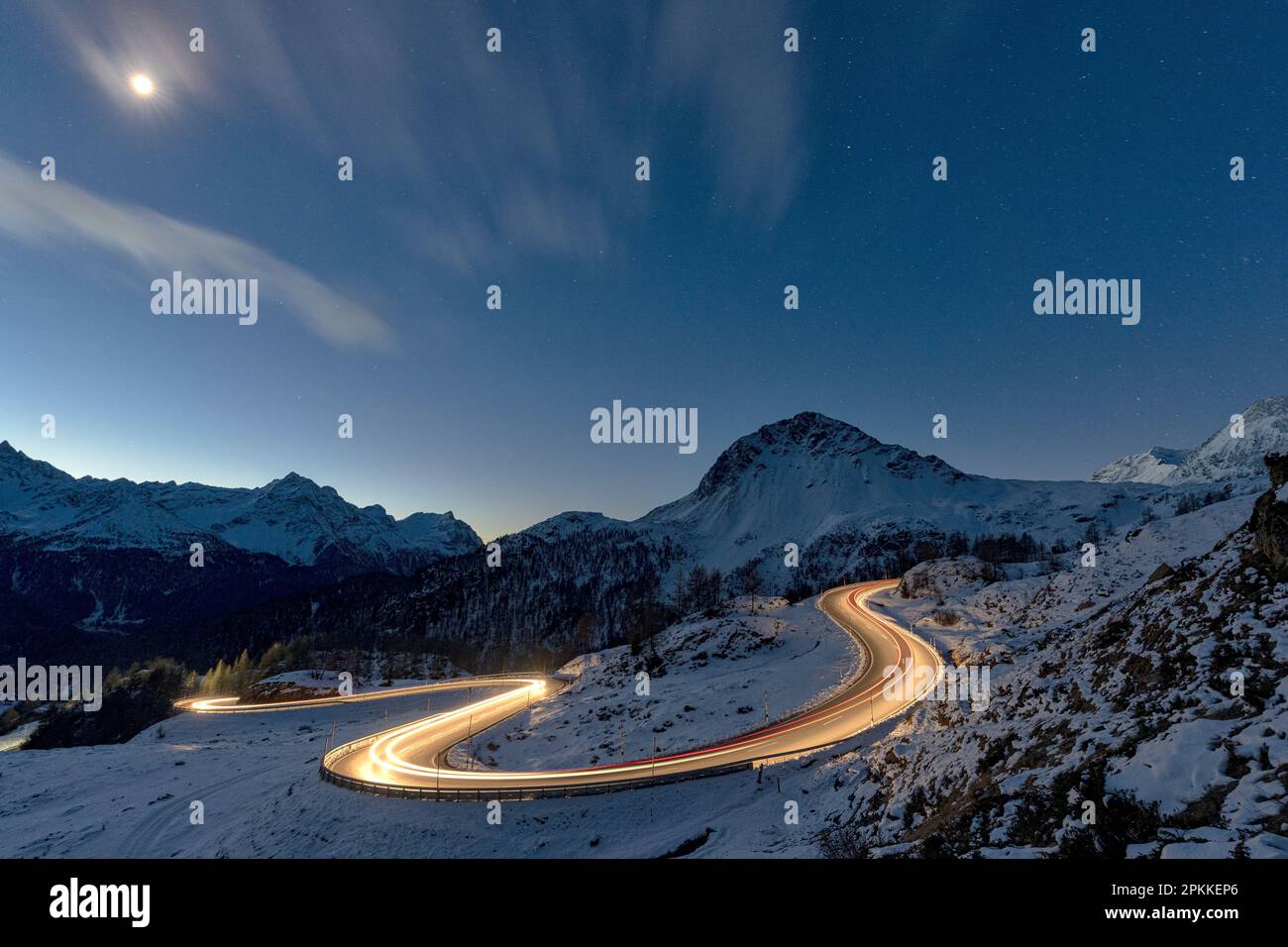 Lichter von Autostrecken auf kurvigen Straßen, die nachts mit Schnee bedeckt sind, Bernina Pass, Val Poschiavo, Kanton Graubunden, Schweiz, Europa Stockfoto