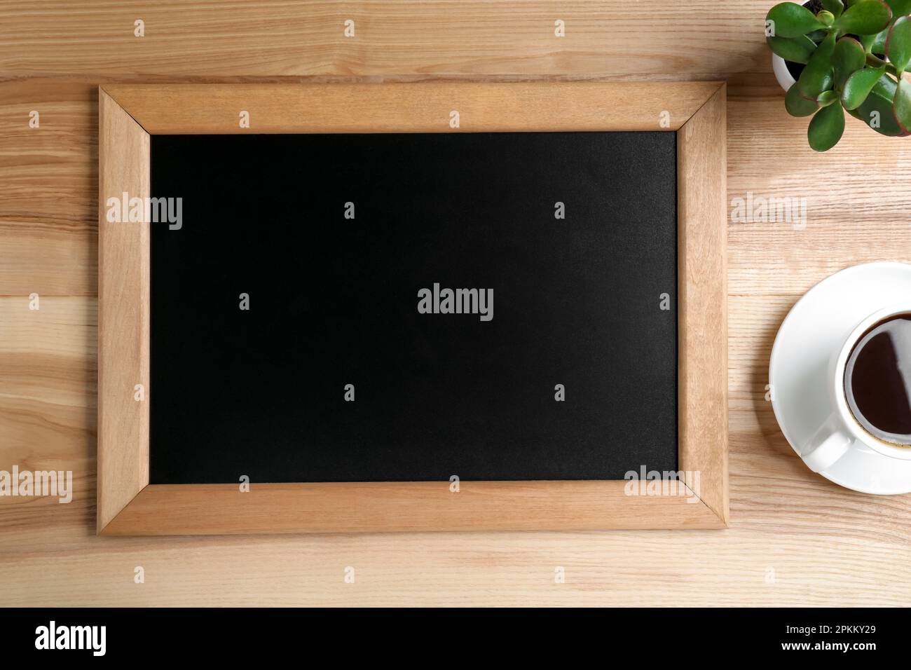 Kleine Tafel, Kaffee und Pflanze auf Holztisch reinigen, flach ablegen Stockfoto