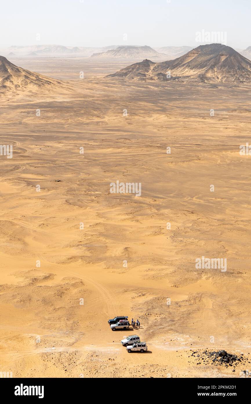 Jeeps parken am Fuße eines Basalthügels auf einem Plateau in der Schwarzen Wüste in Ägypten Stockfoto
