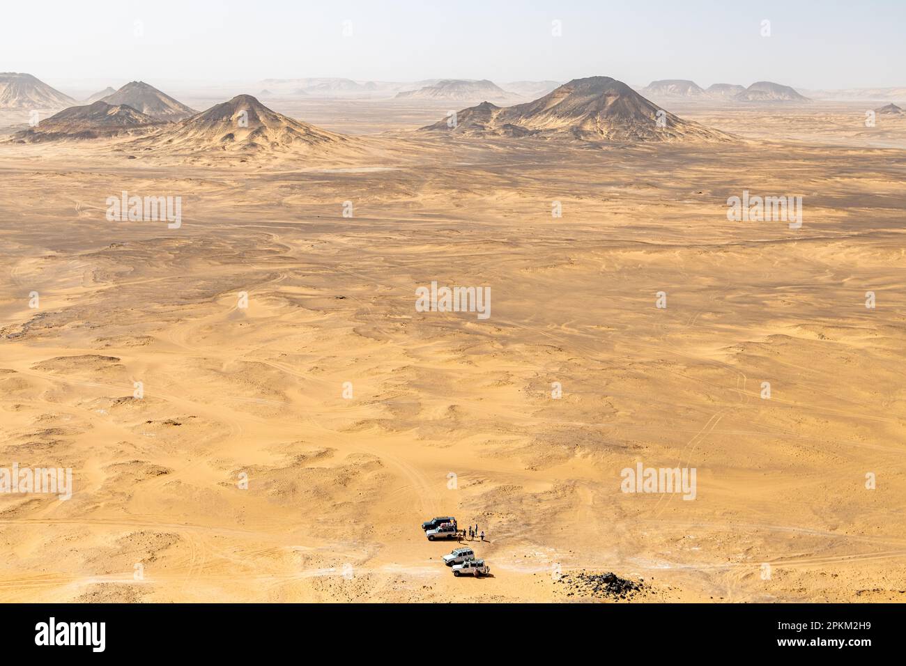 Jeeps parken am Fuße eines Basalthügels auf einem Plateau in der Schwarzen Wüste in Ägypten Stockfoto