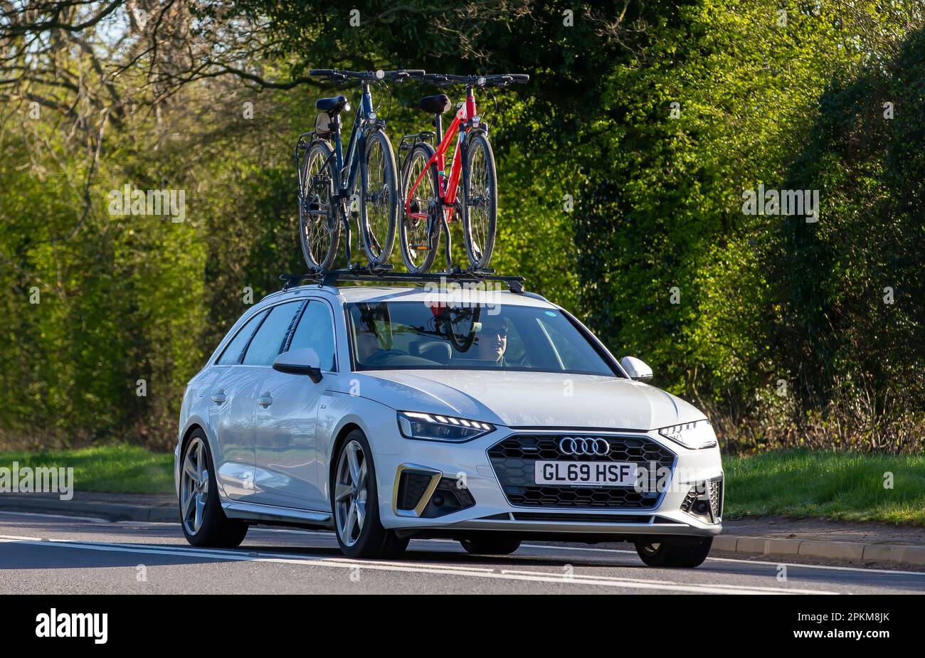 2019 weißer Audi A4 mit zwei Fahrrädern auf dem Dach, die auf einer englischen Landstraße unterwegs sind Stockfoto