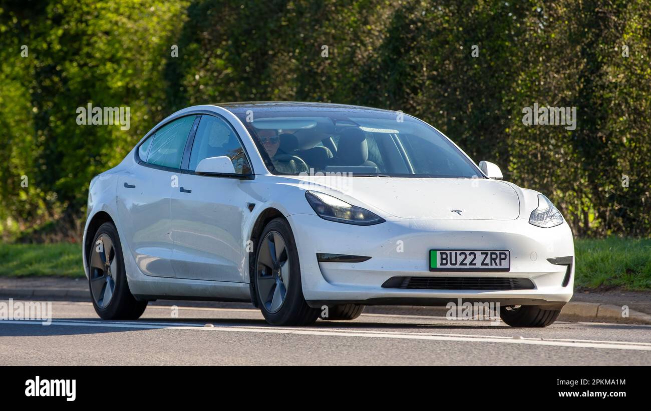 2022 TESLA MODELL 3 STANDARDREICHWEITE + Auto, das auf einer englischen Landstraße fährt Stockfoto