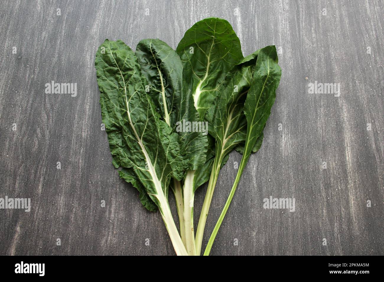 Frisch geerntete große grüne Mangold Blätter bereit zum Zerkleinern und Kochen nahrhafter und gesunder omido auf einem Holztisch Stockfoto