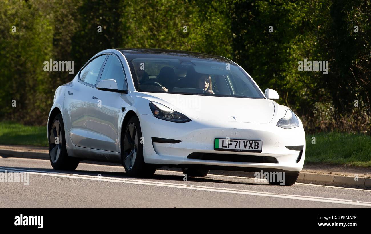 2021 weißer Tesla Model 3 Standard Range, der auf einer englischen Landstraße unterwegs ist Stockfoto
