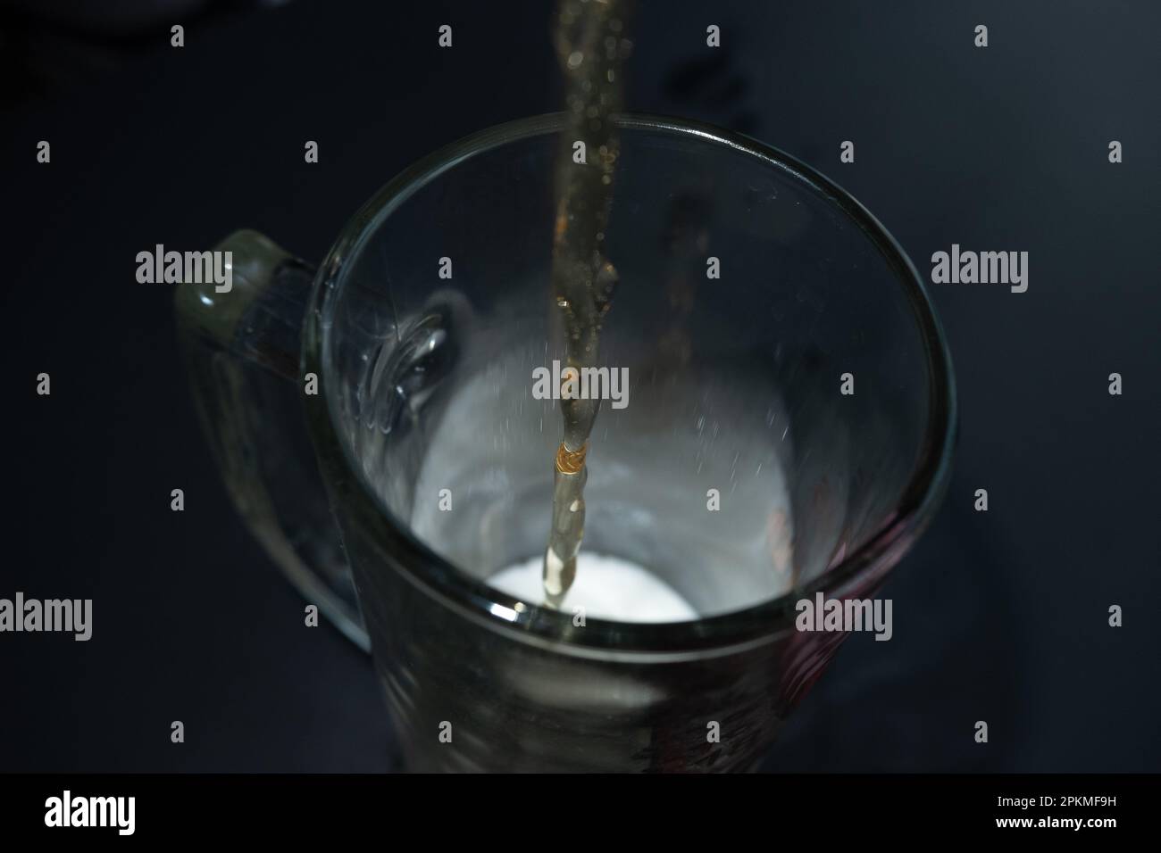 Ein Bierstrom fließt in ein Glas. Dunkler Hintergrund Stockfoto