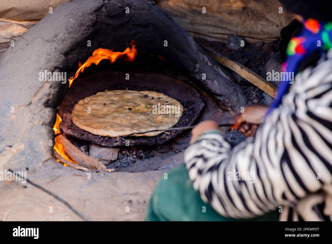 Eine marokkanische Frau kocht eine Berber-Pizza in einem Holzofen Stockfoto