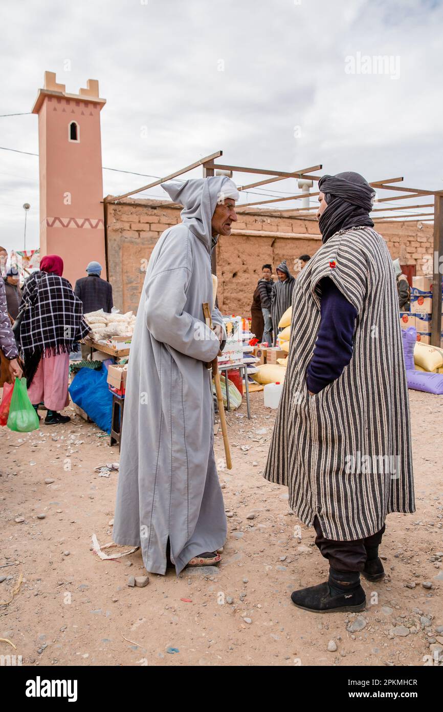 Zwei traditionell gekleidete Männer reden, und Marokkaner versammeln sich auf einem Berbermarkt Stockfoto