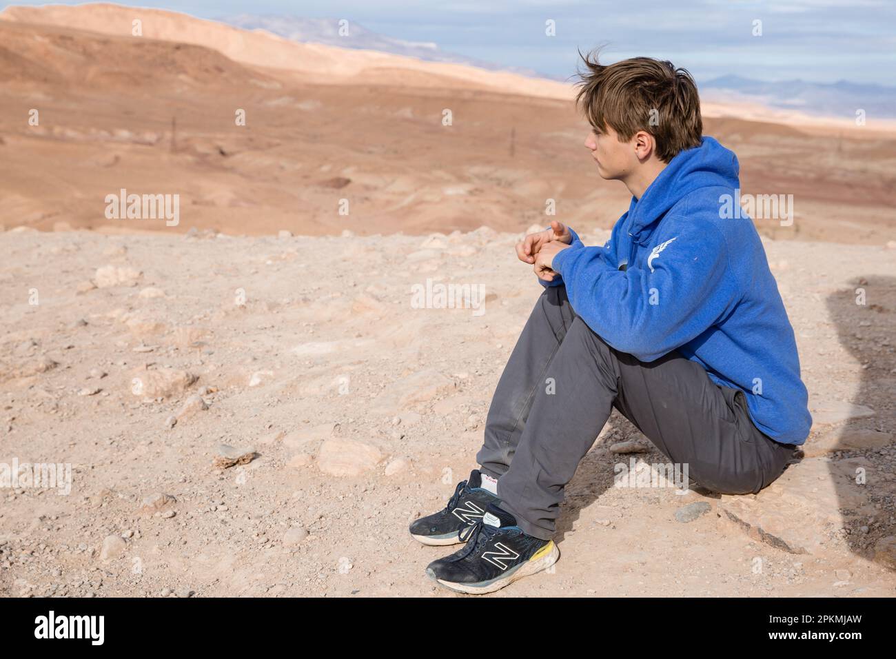 Ein amerikanischer Teenager sitzt und schaut sich die Landschaft in Ait Ben Haddou an Stockfoto