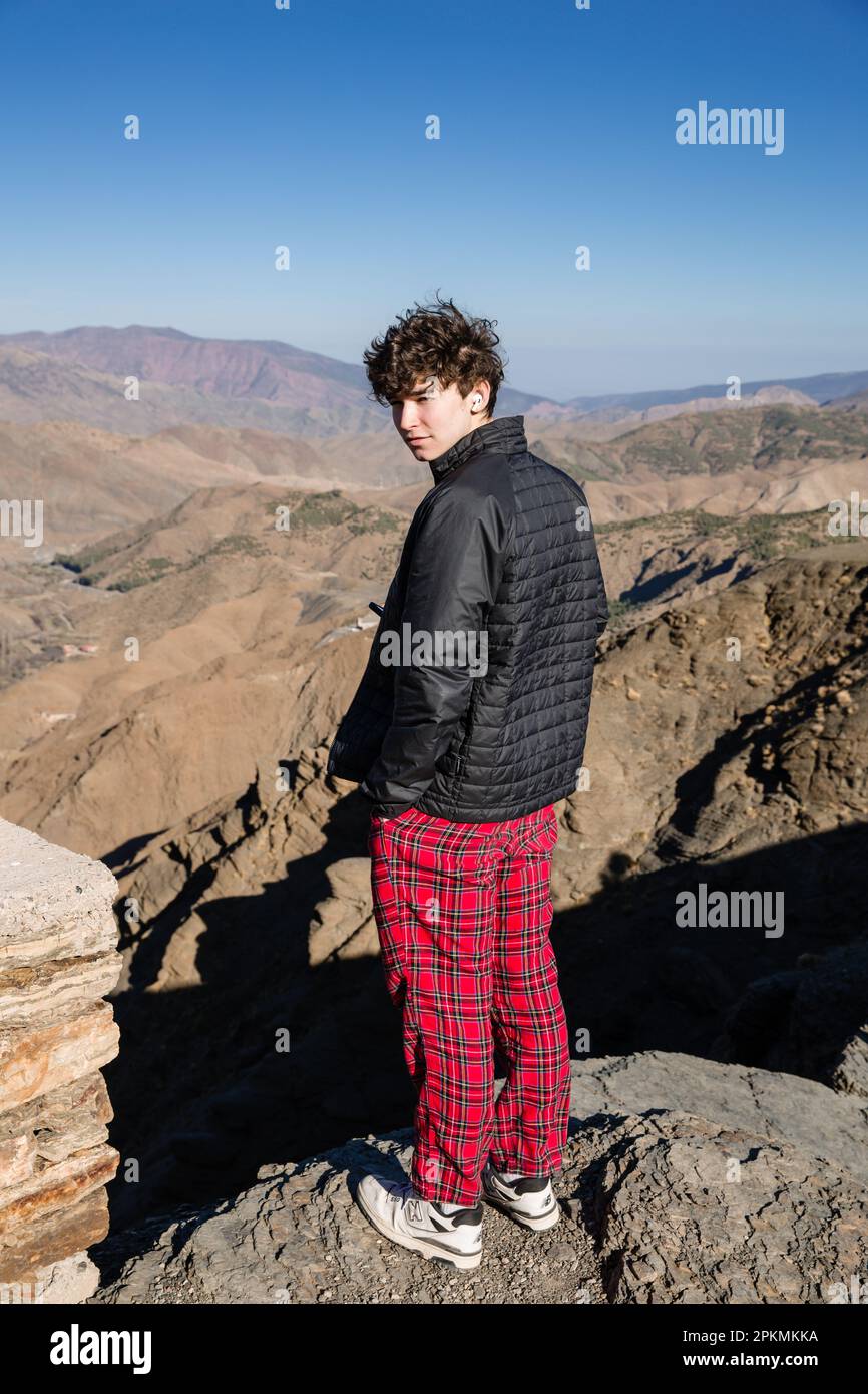 Ein amerikanischer Teenager steht auf einem Felsen im Atlasgebirge und schaut zurück in die Kamera Stockfoto