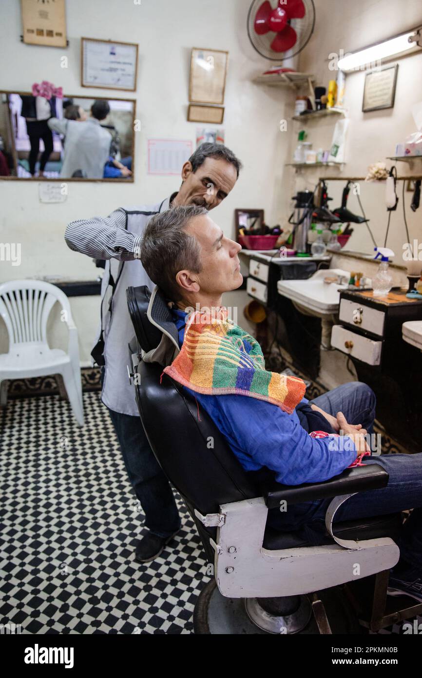 Ein amerikanischer Tourist bekommt eine Rasierrasur in einem Friseursalon in Marrakesch, Marokko Stockfoto