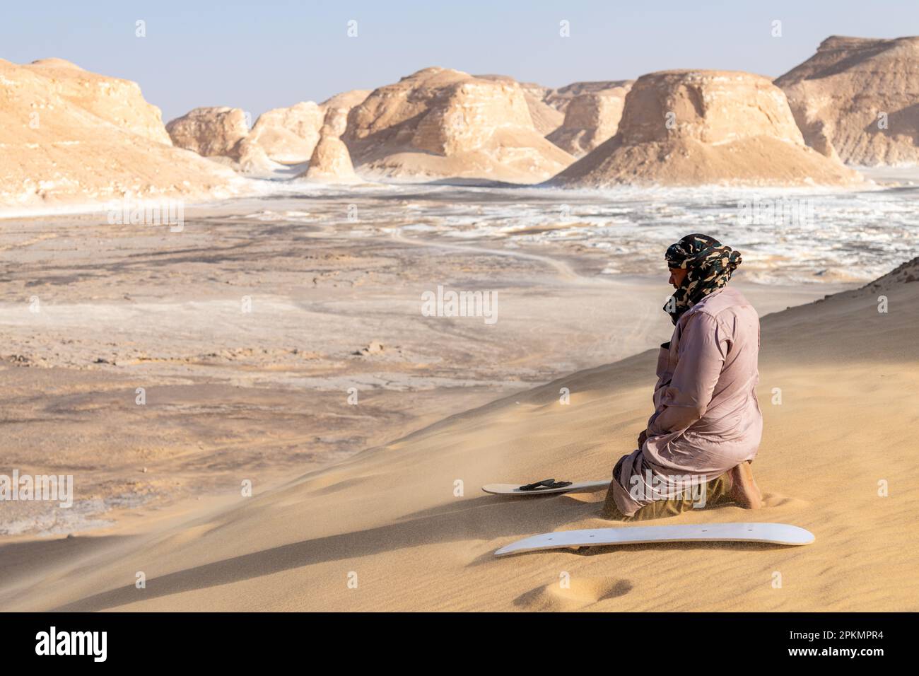 Ein Reiseleiter bereitet ein Brett für einen Touristen vor, der in einer Wüste in der Nähe von Bahariya in Ägypten Sandboarden geht Stockfoto