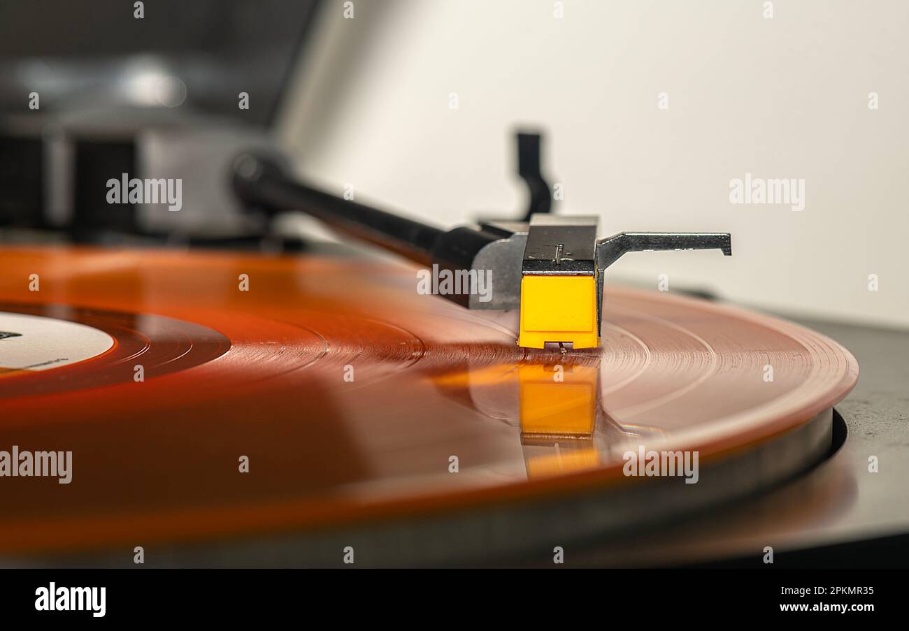 Es gibt einen Melodie-Ton aus, wenn es über die Nadel eines orangefarbenen Plattenspielers mit langer Wiedergabedauer schwebt. Stockfoto