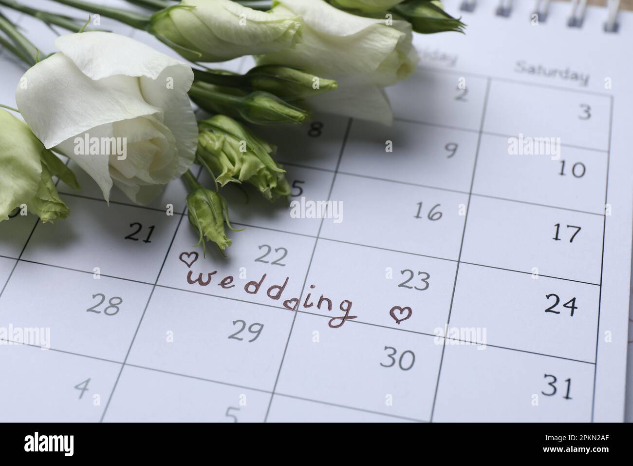 Kalender mit Datumserinnerung zum Hochzeitstag und Blumen, Nahaufnahme Stockfoto