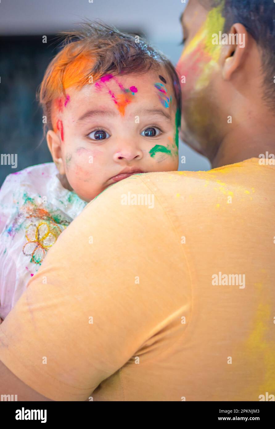 Süßer Säuglingskopf an der Vater-Schulter bei der holi-Feier aus flachem Winkel Stockfoto