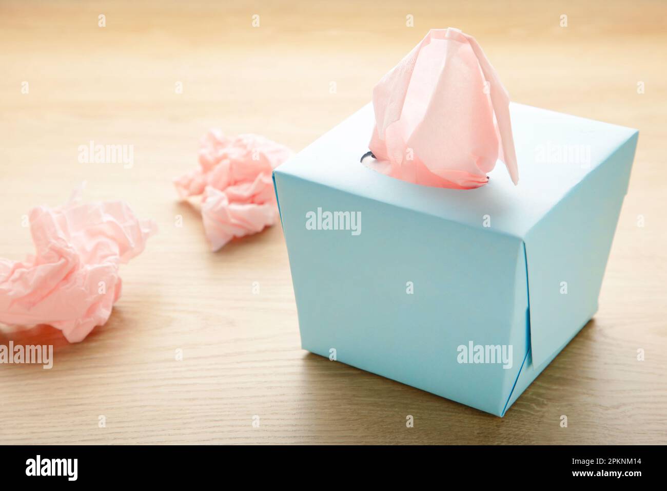 Blaue Box mit Papiertüchern und gebrauchten zerknitterten Servietten auf hellem Hintergrund. Draufsicht Stockfoto