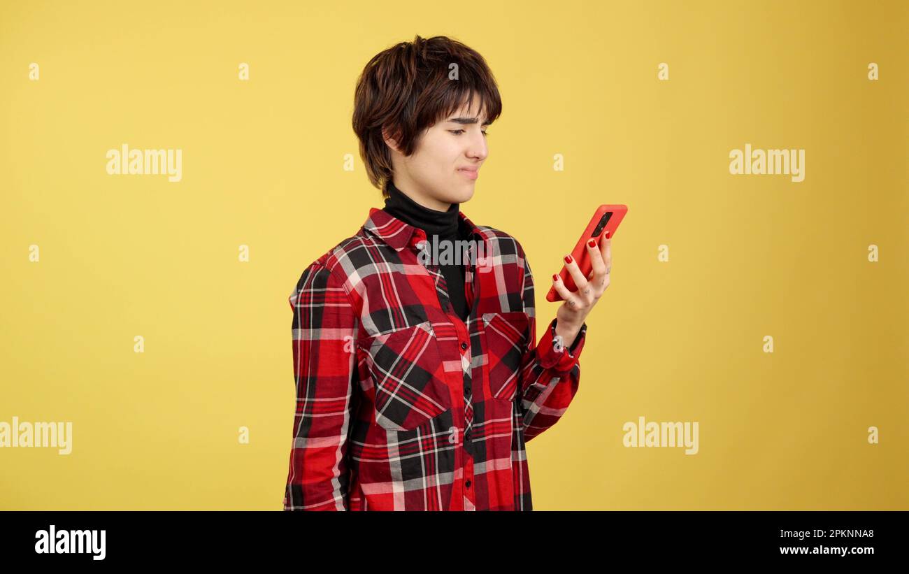 Wütender androgynoser Mensch, der ein Handy benutzt Stockfoto