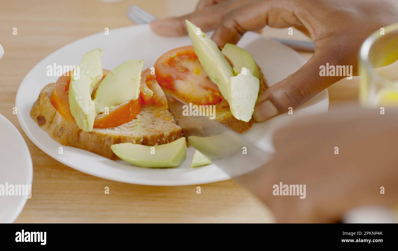 Person schneidet einen gesunden Toast aus Avocado und Tomate Stockfoto