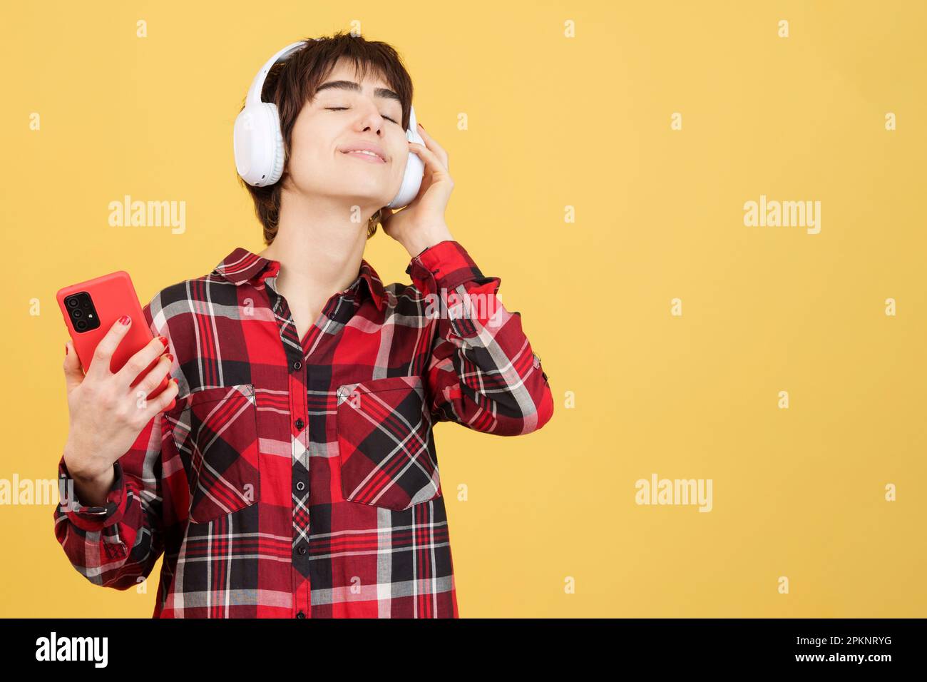 Entspannte androgyne Person, die Musik mit Mobiltelefon und Kopfhörer hört Stockfoto