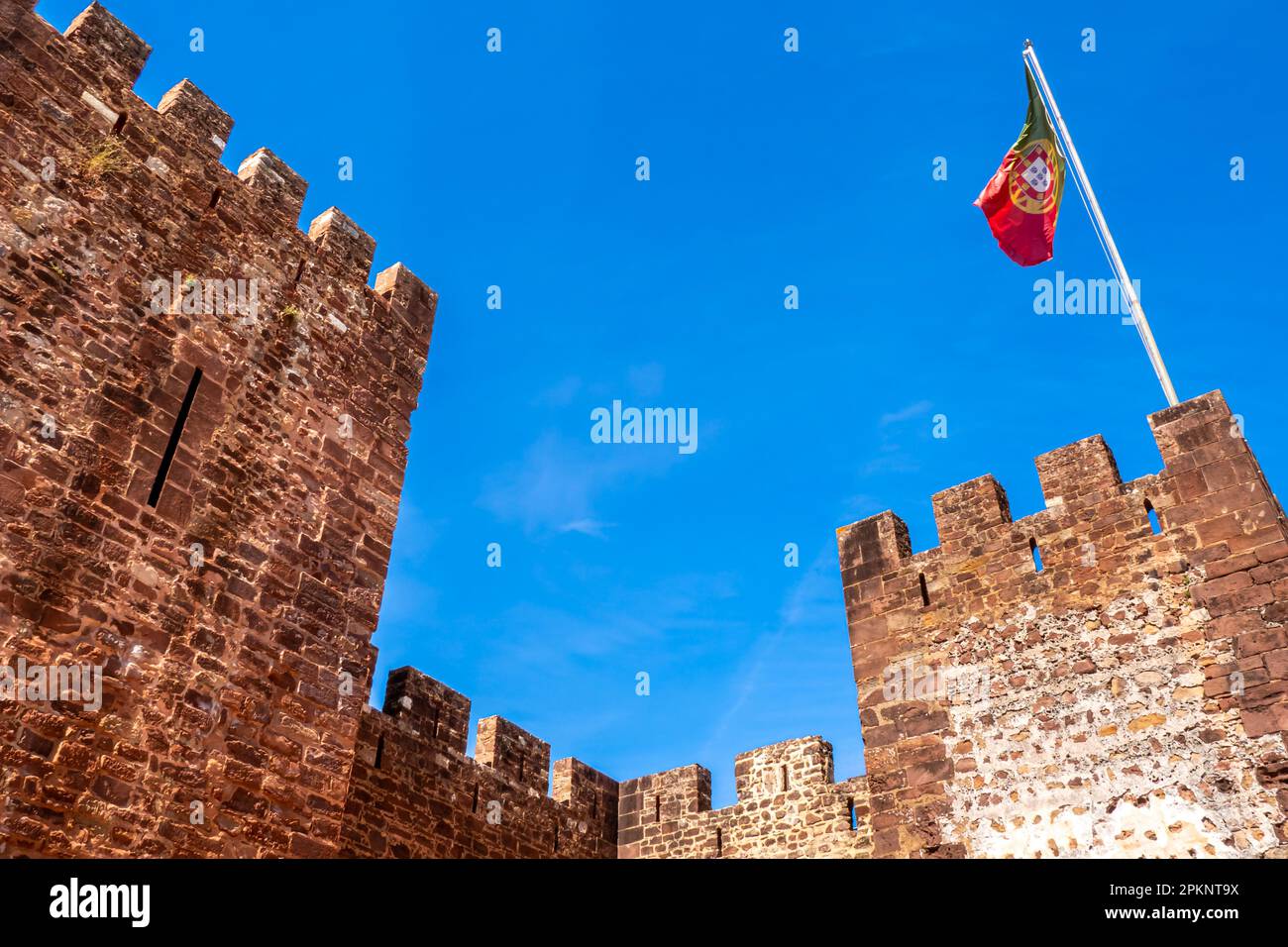 Die beeindruckenden zwei Haupttürme von Castelo de Silves, einer alten maurischen Festung mit massiven Steinmauern, zeigen stolz eine portugiesische Flagge, die winkt Stockfoto