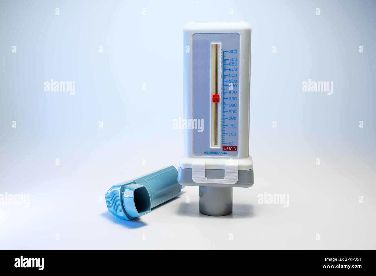 Peak-Flow-Messgerät und blauer Inhalator, medizinische Geräte für Patienten mit Asthmaallergie oder COPD, hellgrauer Hintergrund mit Kopierbereich, ausgewählter Fokus, n Stockfoto