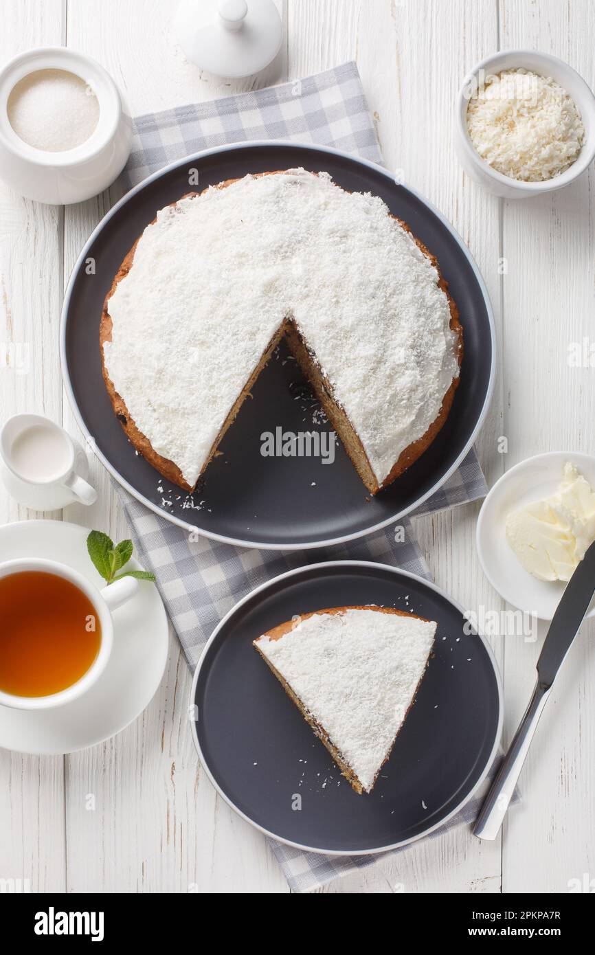 Boston Bun, auch bekannt als Sally Lunn, ist ein großes würziges Brötchen mit einer dicken Schicht Kokosnusseis auf dem Tisch. Vertikale Draufsicht von oben Stockfoto