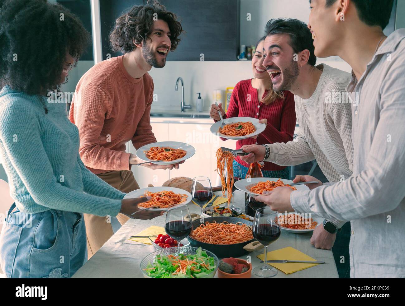 Mann, der seinen Freunden während des Mittagessens im Speisesaal Pasta serviert. Stockfoto