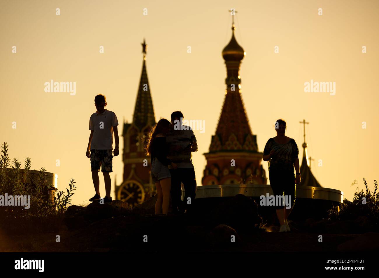 Menschen gehen im Zaryadye Park im Zentrum von Moskau bei Sonnenuntergang, Russland. Dieser Ort ist eine Touristenattraktion von Moskau. Türme der Basilius-Kathedrale und Moskau K. Stockfoto