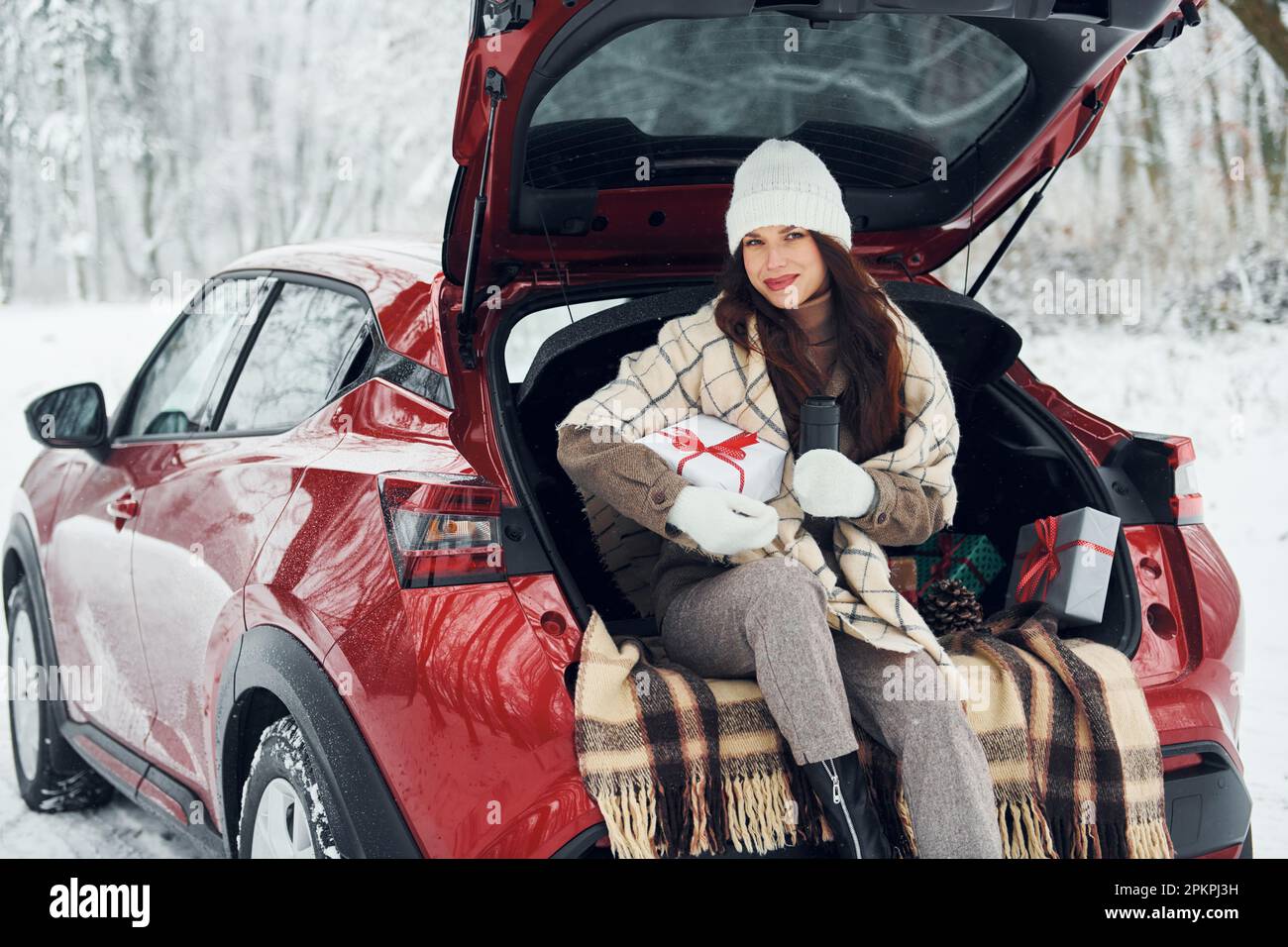 Weihnachtsgeschenke. Schöne junge Frau ist im Winter in der Nähe ihres roten Autos Stockfoto