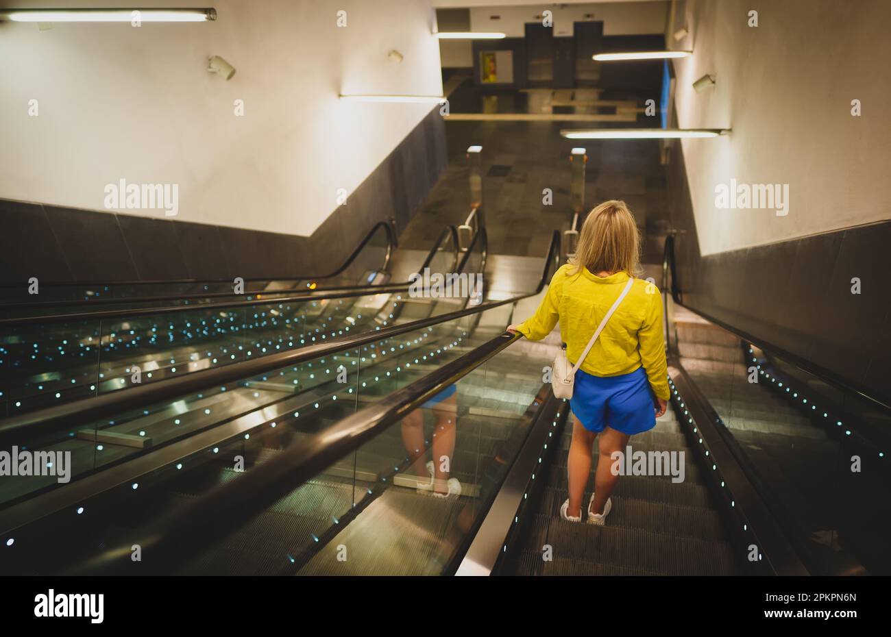 Eine Frau, die die Rolltreppe in der U-Bahn benutzt. Stockfoto