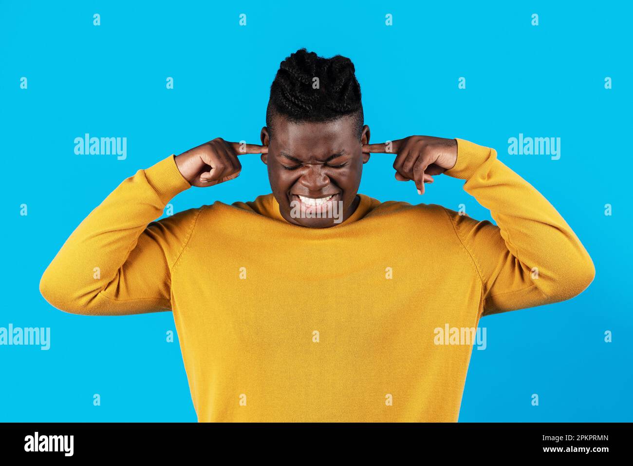 Nerviger junger afroamerikanischer Mann, der mit den Fingern auf blauem Hintergrund Ohren stopft Stockfoto