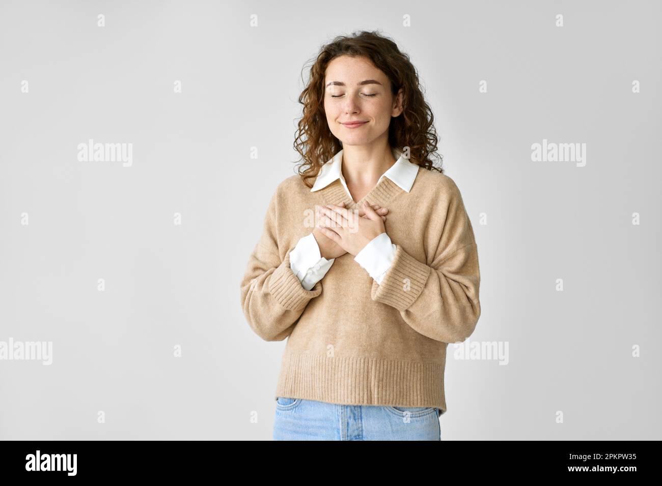 Glückliche junge Frau, die Hände an der Brust hält und Dankbarkeit und Liebe im Herzen spürt. Stockfoto